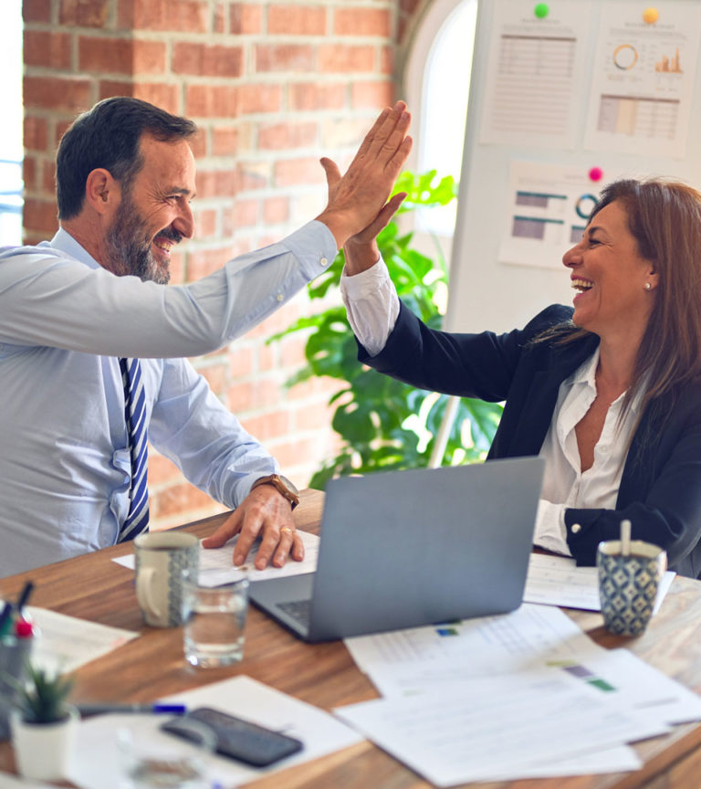 Two business professionals celebrating M&A success and improved business cash-flow.